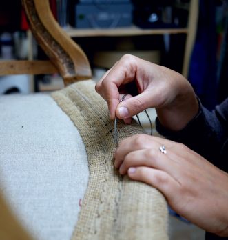 Mains en train de rénover un fauteuil ancien de façon traditionnelle