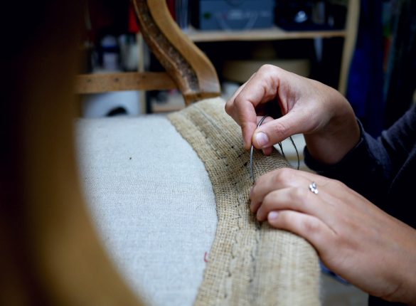 Mains en train de rénover un fauteuil ancien de façon traditionnelle